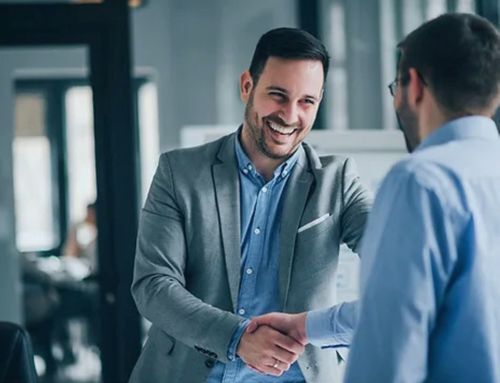 Two professionals shaking hands over architectural plans, representing strong collaboration and partnership in construction engineering projects.
