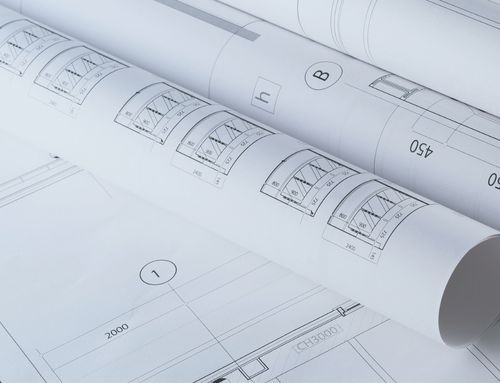 A close-up of architectural plans alongside digital tools, symbolizing the integration of construction engineering expertise with innovative AI-enabled SaaS technology.